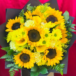 Bouquet of sunflowers, yellow calla lilies, and white blooms in black wrap