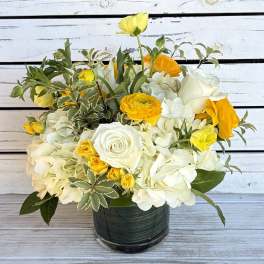 White and yellow flower arrangement in a dark glass vase