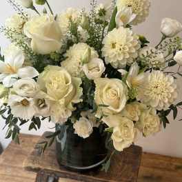 Creamy white bouquet of roses, dahlias, and calla lilies in a dark vase