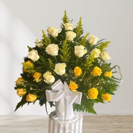 White and yellow roses in a white vase with a satin bow