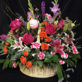 Basket arrangement of pink and orange flowers with a birthday topper