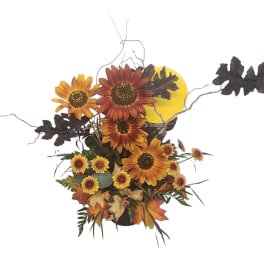 Autumn floral arrangement with sunflowers and fall leaves in a container