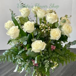 Bouquet of white roses in a clear glass vase with mixed greenery