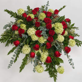Large arrangement of red roses and pale green hydrangeas with trailing greenery