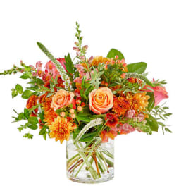 Peach roses and orange flowers in a clear glass vase