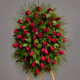 Standing spray of red roses with palm fronds on a gray background