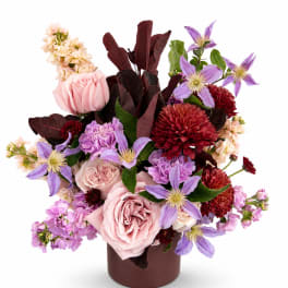 Pink roses and purple flowers arranged in a brown vase