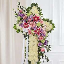 Standing floral cross with pink roses and lilies on a white easel