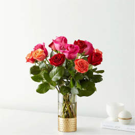Bouquet of pink, red, and orange roses in a clear glass vase