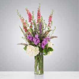 Tall bouquet of pink and purple flowers in a clear glass vase