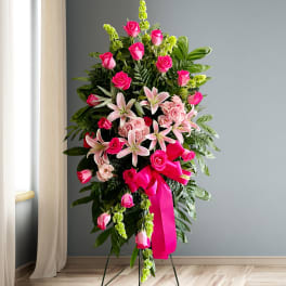 Tall standing floral spray with pink roses and lilies on a ribboned easel