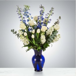 White roses and blue delphinium in a cobalt glass vase