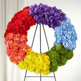 Circular floral wreath in rainbow colors on a black stand