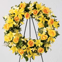 Yellow floral wreath with roses and lilies on a black stand