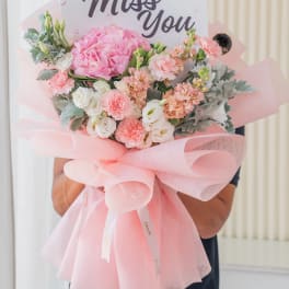 Pink and white bouquet wrapped in pastel pink paper with a thank-you card