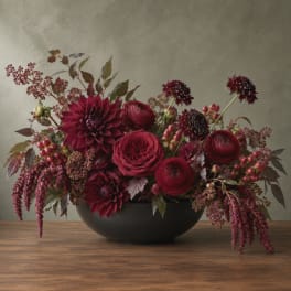 Deep burgundy floral arrangement in a black bowl vase