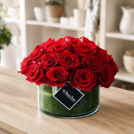 Red roses arranged in a clear glass vase on a table