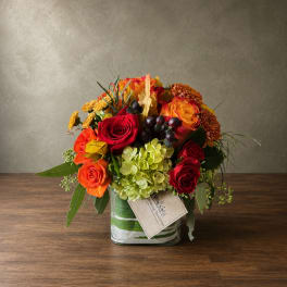 Mixed bouquet of roses, hydrangea, and mums in a glass vase