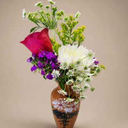 Mixed bouquet in a painted brown vase with white, purple, and red flowers