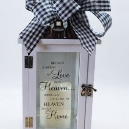 Decorative white lantern with a black-and-white bow and memorial quote