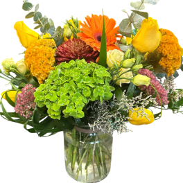 Mixed bouquet in a clear glass vase with yellow, orange, and pink flowers