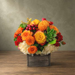Mixed orange and red flower arrangement in a wooden box
