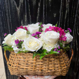 White roses and purple flowers arranged in a wicker basket