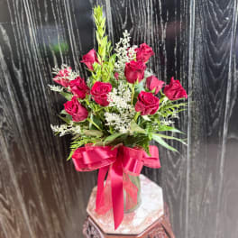 Red roses in a glass vase with a pink ribbon
