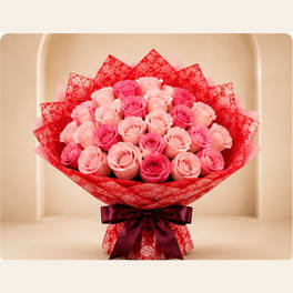Bouquet of pink roses wrapped in red paper with a dark ribbon