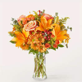 Orange and peach floral bouquet in a clear glass vase