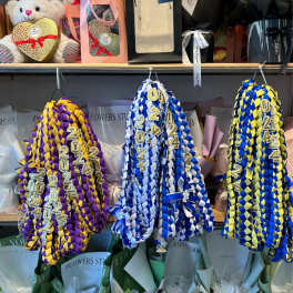 Braided graduation leis in purple-gold, blue-white, and blue-yellow.