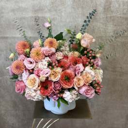 Mixed pink and peach flower arrangement in a white vase