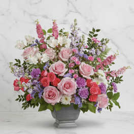Pink roses and mixed flowers arranged in a gray vase