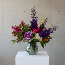 Mixed bouquet of purple, pink, and white flowers in a glass vase