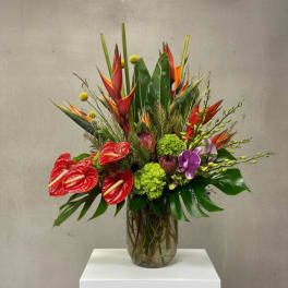 Tropical flower arrangement in a glass vase with red anthuriums and purple orchids
