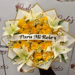 Yellow roses with white lilies and small white daisies in a wrapped bouquet