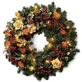 Evergreen wreath with cream flowers, red berries, pinecones, and warm string lights on a circular base