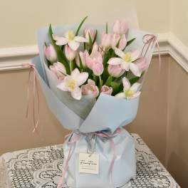 Pink tulips and white flowers wrapped in pale blue paper with pink ribbons