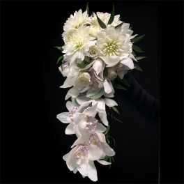 White cascading bouquet with orchids and dahlias against a black background