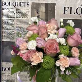 Pink and peach bouquet with roses, tulips, carnations, and green pom flowers in a glass vase