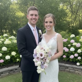 Bride and groom posing with a white and blush wedding bouquet outdoors