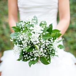 Bride holding a white bouquet with baby's breath and green leaves