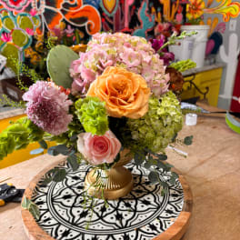 Mixed bouquet in a gold vase with pink and peach blooms