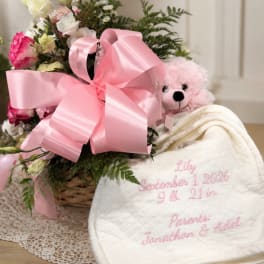 Pink and white flower basket with a teddy bear and embroidered baby blanket