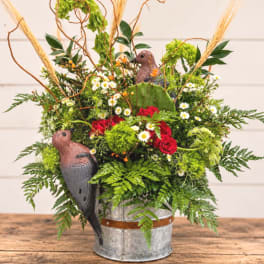Mixed floral arrangement in a metal bucket with bird decorations