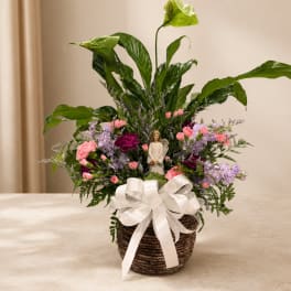 Mixed pink and lavender flowers in a woven basket with a white ribbon