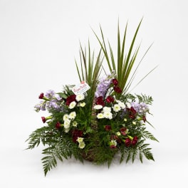 Basket arrangement with red, white, and lavender flowers and tall palm fronds