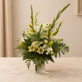 White and yellow floral arrangement in a clear glass vase