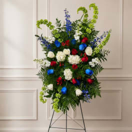 Tall floral standing spray with red, white, blue, and green blooms on an easel