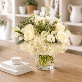 Cream rose and hydrangea arrangement in a clear glass vase